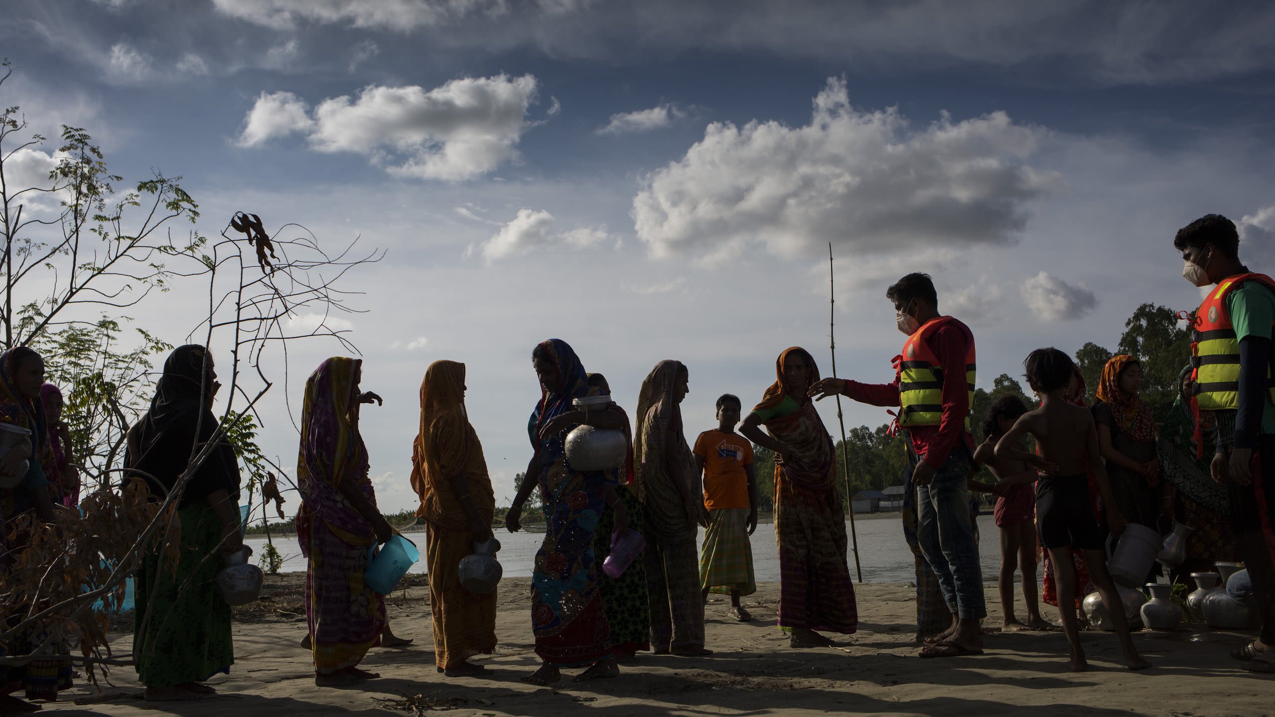 Tangail, Bangladesh, August 2020. Red Crescent volunteers provide char-dwellers with safe water as they search for what’s left of their sandbank homes after another round of devastating floods. (A.J. Ghani/Bangladesh Red Crescent Society)